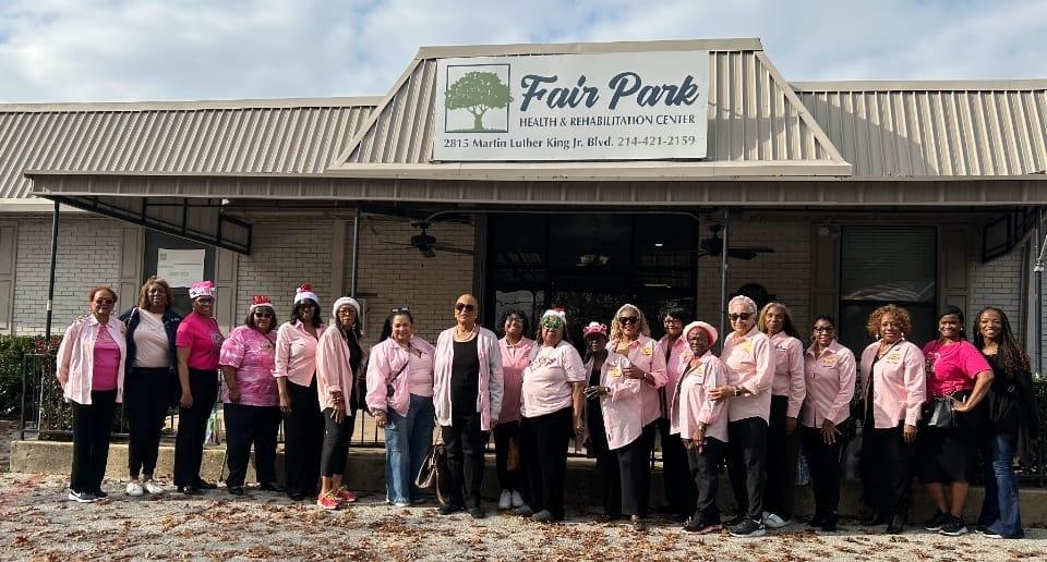 Ladies of the Dallas Chapter, dressed in pink and some in holiday hats, gathered outside Fair Park Health and Rehabilitation Center