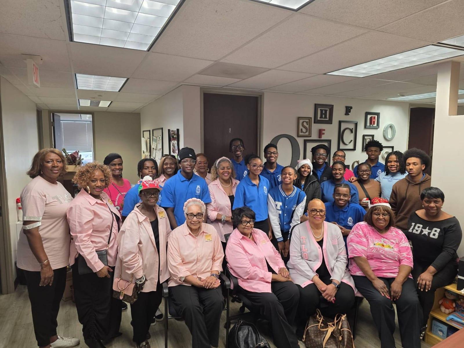 Ladies of the Dallas Chapter in pink and Top Teens in royal blue shirts gathered together indoors